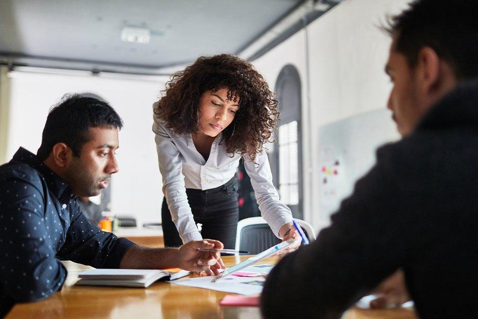 Female data analyst discussing insights with colleagues in a meeting room.